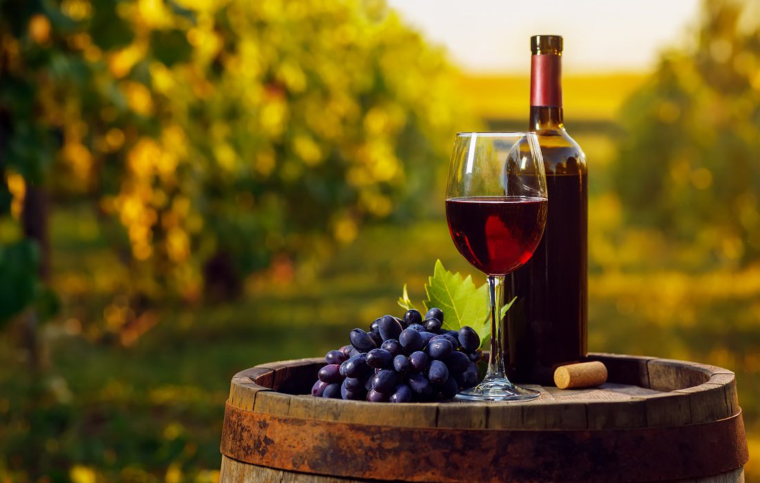 Wine bottle and glass on wooden barrel.