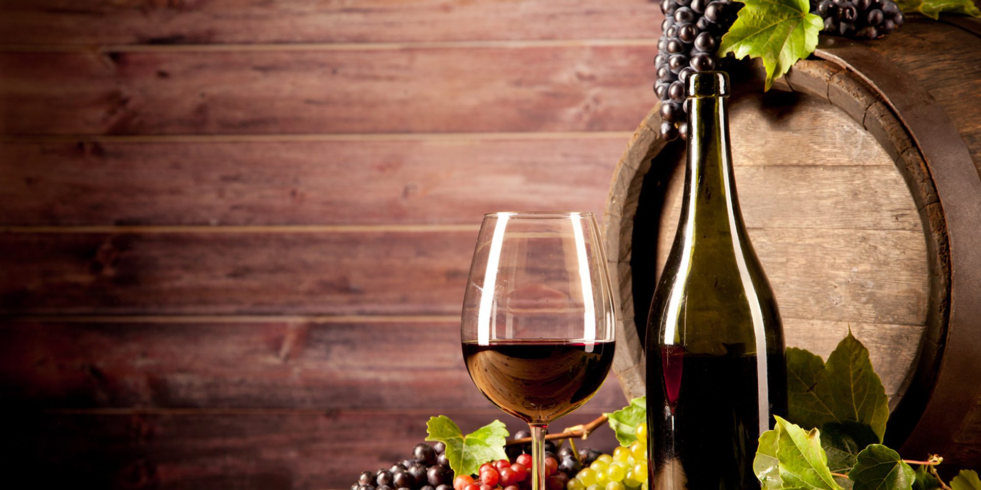 Red wine and grapes by wooden barrel